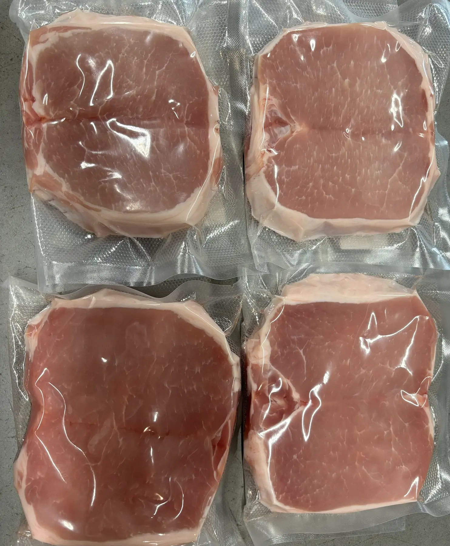Four raw meat slices wrapped in plastic ready to be cooked.