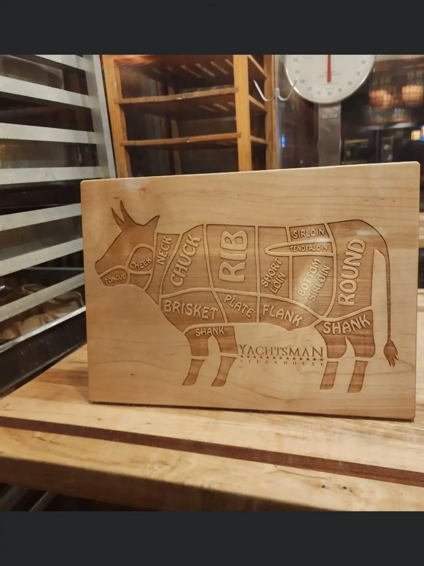 A wooden cutting board with the cuts of meat on it.